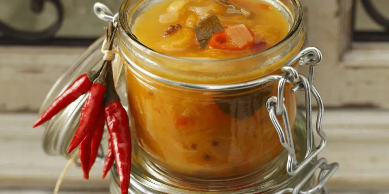 Ein Glas mit leckerem Aprikosen-Chutney-Rezept, garniert mit roten Chilis. Perfekt für herzhafte Gerichte.