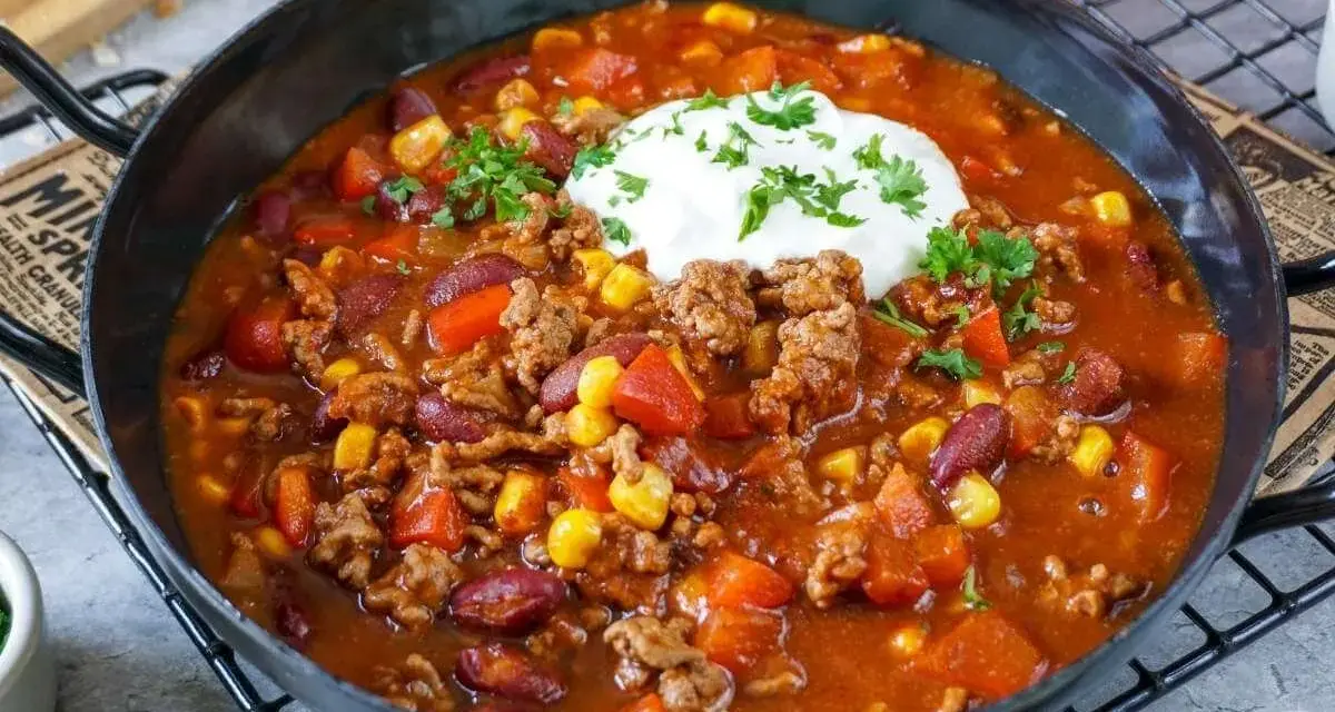 Herzhaftes Chili con Carne mit Hackfleisch, Kidneybohnen, Mais und Paprika, garniert mit einem Klecks Sauerrahm und Petersilie.