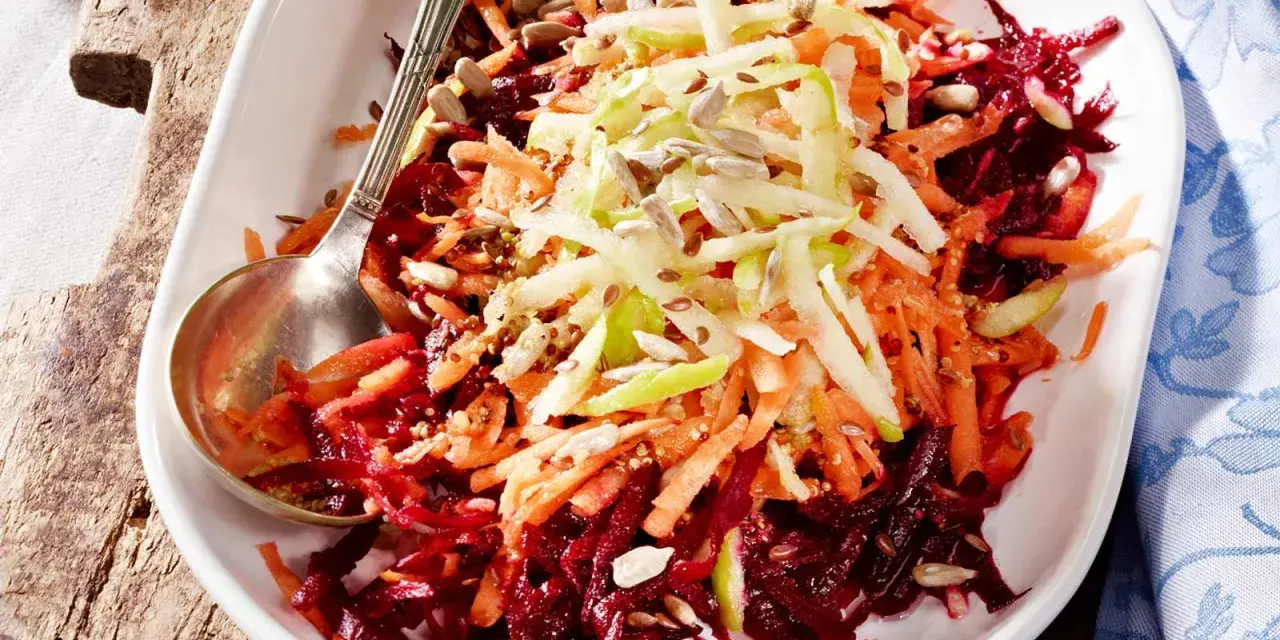 Bunter Salat aus geraspelter roter Bete, Karotten und Apfel, garniert mit Sonnenblumenkernen.
