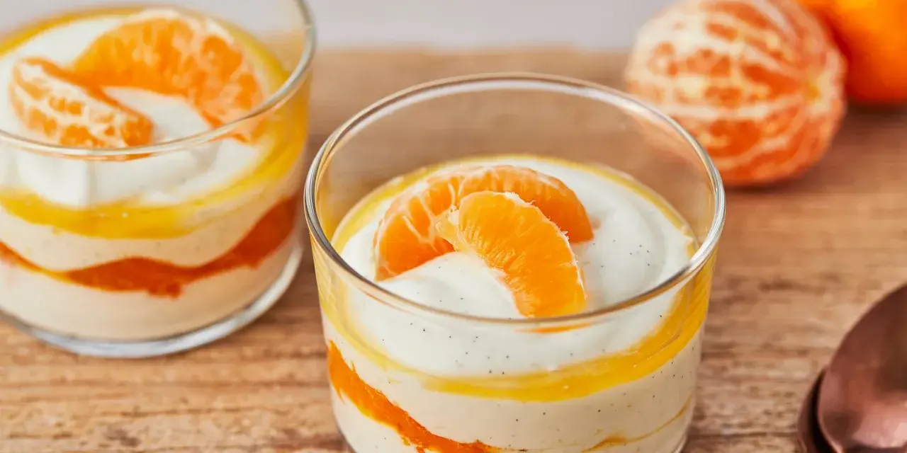 Zwei Gläser mit cremiger Quarkspeise mit Mandarinen, garniert mit frischen Mandarinenspalten.