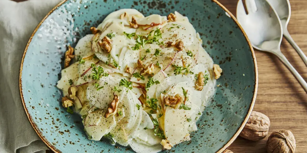 Ein erfrischender rettichsalat mit apfel, garniert mit Walnüssen und Petersilie, auf einem türkisfarbenen Teller.