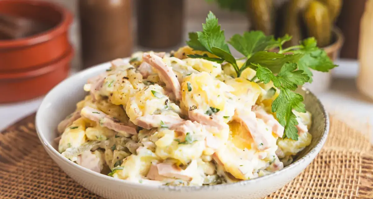 Schüssel mit Kartoffelsalat mit Miracel Whip, Schinken und Petersilie. Dazu passen Gewürzgurken.
