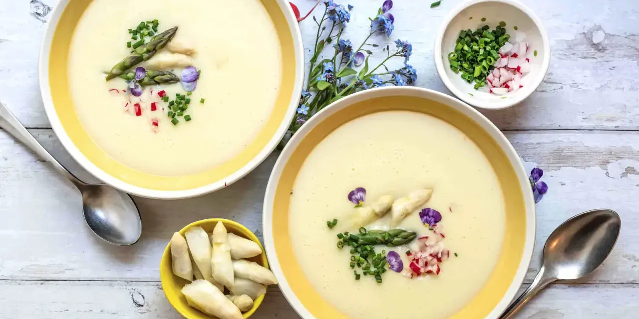 Cremige Spargelsuppe, ein einfaches Rezept für den Frühling. Garniert mit Spargelspitzen, Radieschen und Schnittlauch.