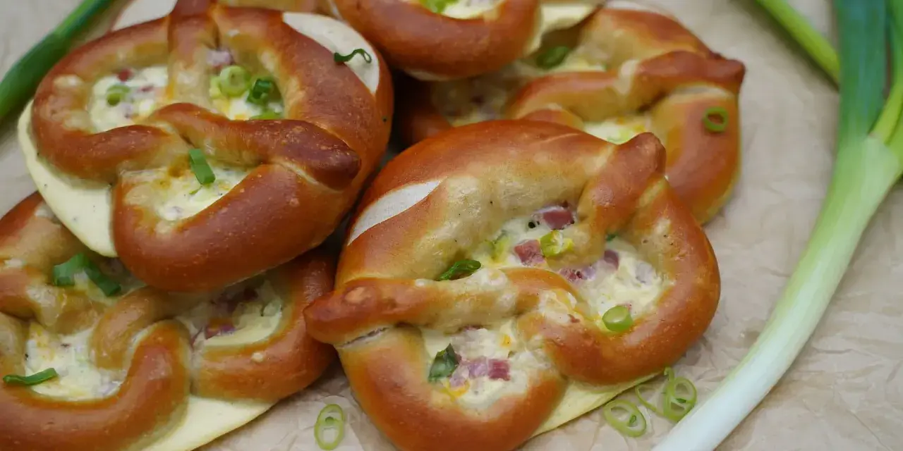 Herzhafte Brezeln gefüllt mit Käse und Speck, perfekt als partyrezepte aus dem ofen zum vorbereiten. Mit Frühlingszwiebeln garniert.