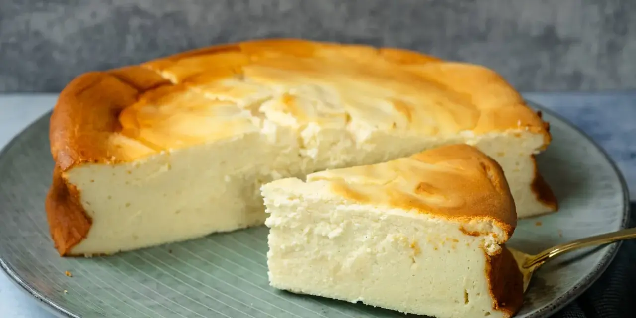 Saftiger Kuchen mit 250g Quark und Vanillepudding, goldbraun gebacken, auf einem Teller mit einem Stück daneben.
