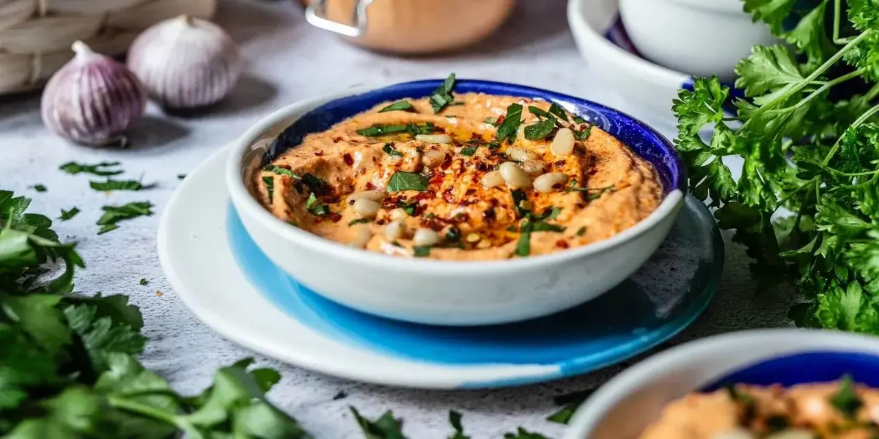 Cremiger Feta Paprika Dip mit Pinienkernen und frischer Petersilie, garniert mit Chiliflocken. Perfekt zum Dippen!
