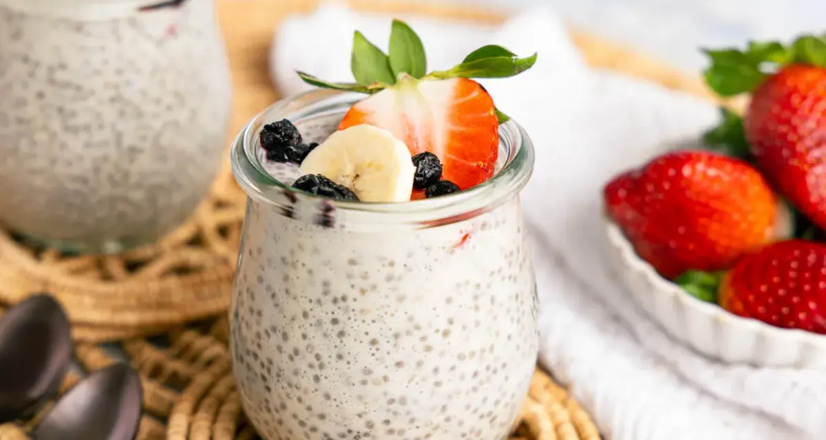 Leckerer Chia Pudding mit Milch, garniert mit Erdbeeren, Bananen und Blaubeeren. Ein gesunder Genuss!