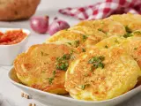 Goldbraune Kartoffelpuffer, garniert mit Petersilie, sind ein köstliches Beispiel für Rezepte mit Kartoffeln als Hauptspeise. Dazu passen Tomatensoße und Zwiebeln.