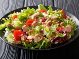 Frischer Thunfischsalat mit knackigem Salat, Tomaten und Bohnen auf schwarzem Teller.