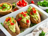 Gefüllte Süßkartoffeln mit Avocado-Topping. Leckere, kalte Rezepte mit Avocado, garniert mit Paprika und Kräutern.