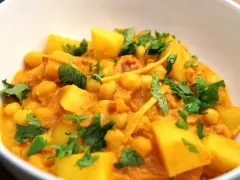 Herzhaftes Kichererbsen Curry mit Kartoffelstücken und frischem Koriander, ein Genuss für die Sinne.