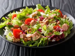 Frischer Thunfischsalat mit knackigem Salat, Tomaten und Bohnen auf schwarzem Teller.