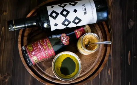 Zutaten für ein köstliches Balsamico-Dressing: eine Flasche Olivenöl, eine Flasche Aceto Balsamico Giuseppe Giusti und eine Schale mit grünen Kräutern.