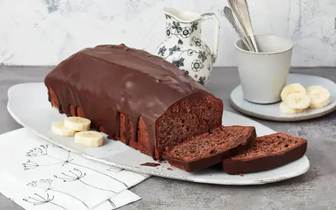 Saftige Schoko-Bananen-Torte mit dunkler Schokoladenglasur, garniert mit Bananenscheiben. Ein Genuss für jeden Kaffeetisch.