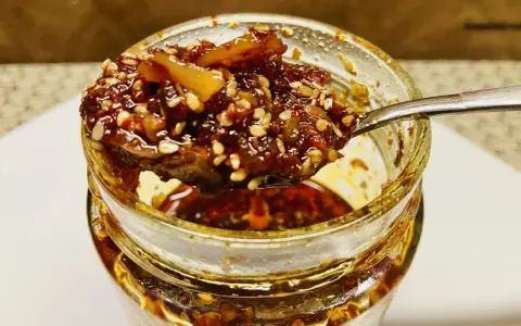 Ein Löffel voller knusprigem Chiliöl mit Sesam und Gewürzen, bereit, Gerichte zu verfeinern.
