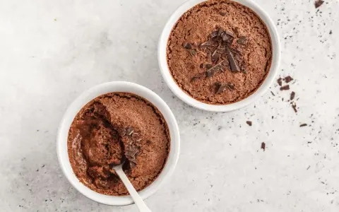 Zwei Schokoladenmousse-Portionen, garniert mit Schokostückchen. Ein Löffel steckt in einer der Schalen, bereit für ein schnelles Dessert.
