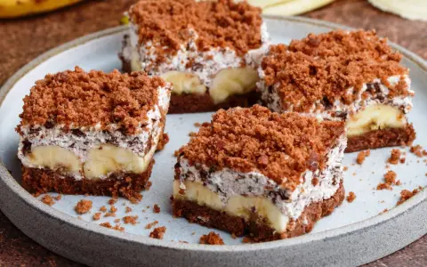 Vier Stücke saftiger Maulwurfkuchen vom Blech mit Bananen und Schokoladenstreuseln auf einem Teller.