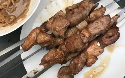 Saftige Fleischspieße, perfekt gegrillt, wie beim besten russischen Schaschlik Rezept. Dazu eine Schüssel mit marinierten Zwiebeln.
