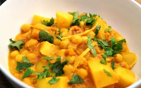 Herzhaftes Kichererbsen Curry mit Kartoffelstücken und frischem Koriander, ein Genuss für die Sinne.