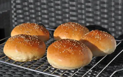 Fünf goldbraune Burgerbrötchen mit Sesam, frisch gebacken nach einem tollen burger buns rezept.