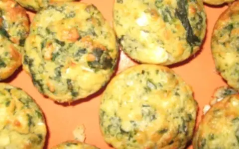Saftige Spinat Feta Muffins, goldbraun gebacken, mit sichtbaren grünen Spinatstückchen und weißen Feta-Käse-Einlagen.