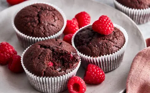 Saftige schoko himbeer muffins auf einem Teller, garniert mit frischen Himbeeren. Ein Genuss für alle Sinne!