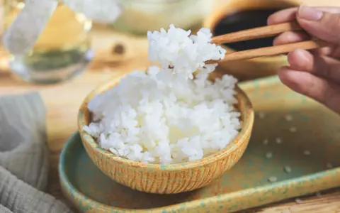 Perfekter sushi reis im reiskocher, dampfend und bereit, mit Stäbchen gegriffen zu werden. Ein Hauch von Asien auf dem Tisch.