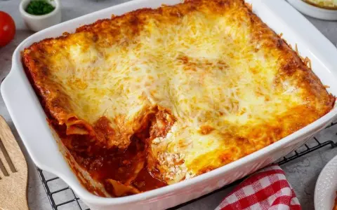 Herzhafte Lasagne mit Schmand und goldbraun überbackenem Käse in einer weißen Auflaufform.