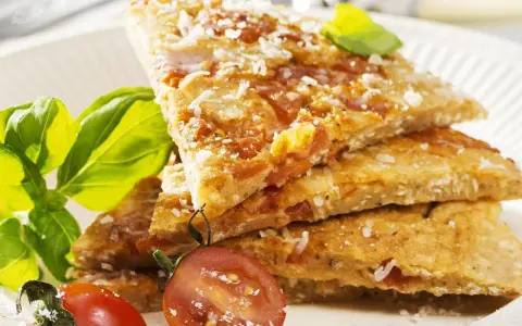 Herzhafte Hauptspeise: knusprige Eierkuchen-Schnitten mit Tomaten und Parmesan, garniert mit Basilikum und Kirschtomaten.