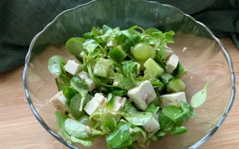 Erfrischender weintrauben feta salat mit Gurkenwürfeln und Sonnenblumenkernen in einer Glasschüssel.