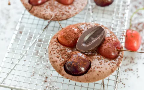 Schokoladen-Clafoutis mit Kirschen und Schokostückchen, ein köstliches clafoutis rezept original, bestäubt mit Kakaopulver.