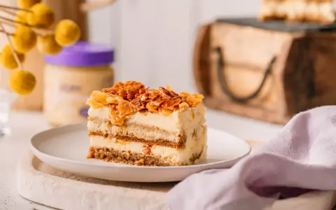 Ein Stück Bienenstich Tiramisu mit karamellisierten Mandeln und cremiger Füllung auf einem Teller.