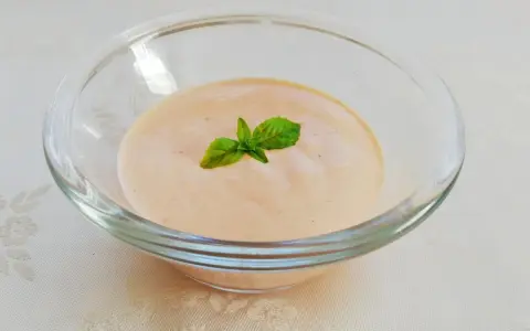 Cremiges Sugo Aurora in einer Glasschale, garniert mit frischem Basilikum.