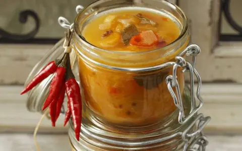 Ein Glas mit leckerem Aprikosen-Chutney-Rezept, garniert mit roten Chilis. Perfekt für herzhafte Gerichte.