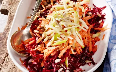 Bunter Salat aus geraspelter roter Bete, Karotten und Apfel, garniert mit Sonnenblumenkernen.