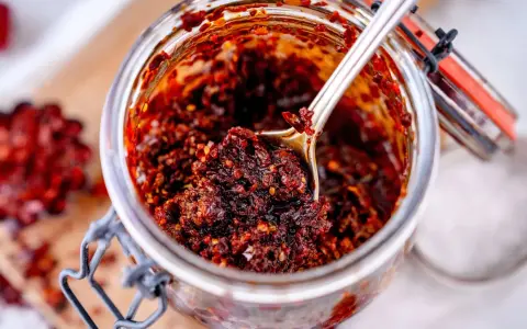 Ein Glas mit würzigem Chili Crunch, perfekt für jedes Chili Crunch Rezept. Eine Löffelspitze voller Geschmack!