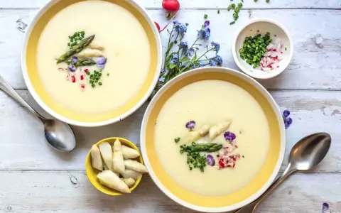 Cremige Spargelsuppe, ein einfaches Rezept für den Frühling. Garniert mit Spargelspitzen, Radieschen und Schnittlauch.