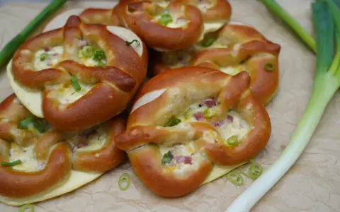 Herzhafte Brezeln gefüllt mit Käse und Speck, perfekt als partyrezepte aus dem ofen zum vorbereiten. Mit Frühlingszwiebeln garniert.