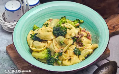 Eine Schüssel mit Tortellini in cremiger Sauce, garniert mit Brokkoli und Speck. Perfekt für eine schnelle Sauce zu Tortellini.