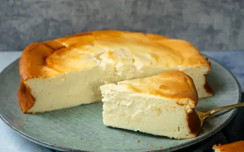 Saftiger Kuchen mit 250g Quark und Vanillepudding, goldbraun gebacken, auf einem Teller mit einem Stück daneben.