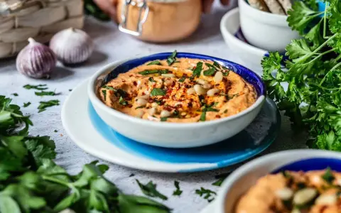 Cremiger Feta Paprika Dip mit Pinienkernen und frischer Petersilie, garniert mit Chiliflocken. Perfekt zum Dippen!