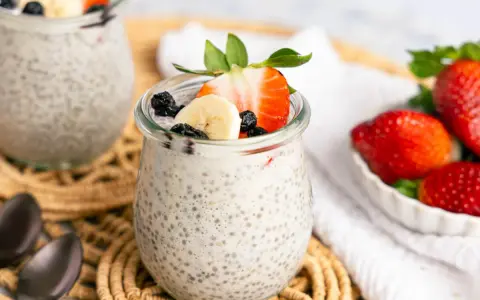 Leckerer Chia Pudding mit Milch, garniert mit Erdbeeren, Bananen und Blaubeeren. Ein gesunder Genuss!