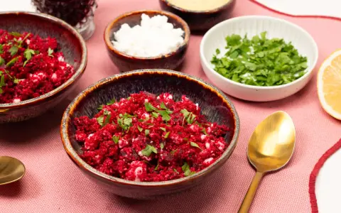 Rote Bete Couscous Salat mit Feta und Petersilie, garniert mit Zitronenspalte.
