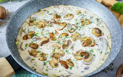 Cremige champignon rahm sauce in einer Pfanne, garniert mit frischer Petersilie. Ein Genuss für jeden Pilzliebhaber!