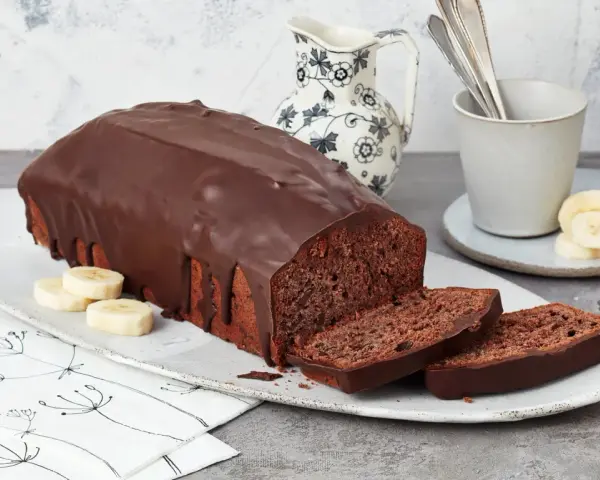 Saftige Schoko-Bananen-Torte mit dunkler Schokoladenglasur, garniert mit Bananenscheiben. Ein Genuss für jeden Kaffeetisch.