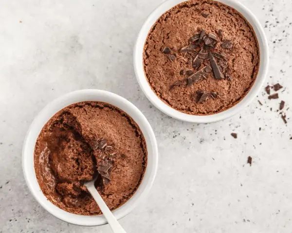 Zwei Schokoladenmousse-Portionen, garniert mit Schokostückchen. Ein Löffel steckt in einer der Schalen, bereit für ein schnelles Dessert.