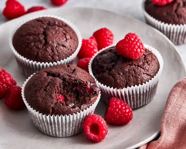 Saftige schoko himbeer muffins auf einem Teller, garniert mit frischen Himbeeren. Ein Genuss für alle Sinne!