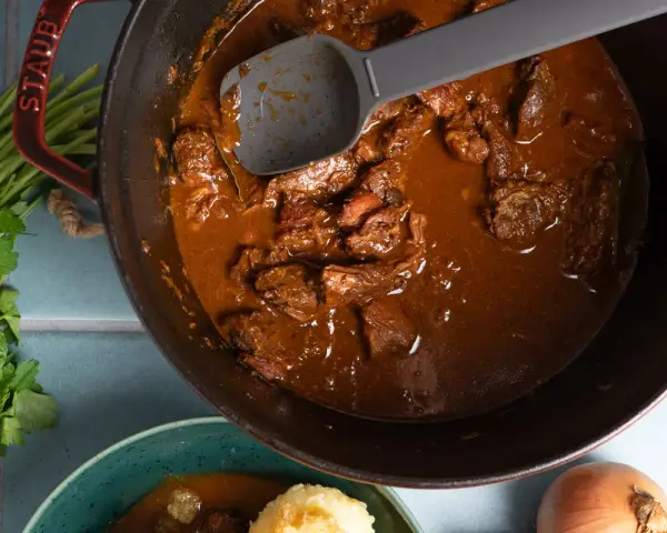 Herzhaftes Gulasch im Gusseisentopf, das beste Gulasch Rezept original Oma. Mit Petersilie und Zwiebeln.