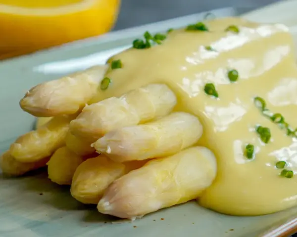 Spargel mit cremiger Sauce Hollandaise, garniert mit Schnittlauch. Ein Klassiker der Frühlingsküche.