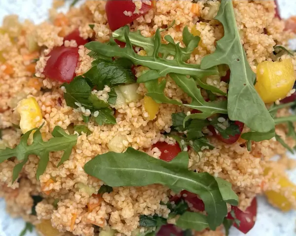 Frischer Couscous-Salat mit Tomaten, Gurken, Paprika und Rucola. Ein leichter und gesunder Genuss.